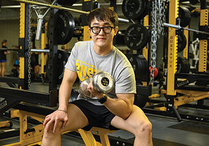 Student lifting weights in gym. Links to Beneficiary Designations Student lifting weights in gym. Links to Beneficiary Designations